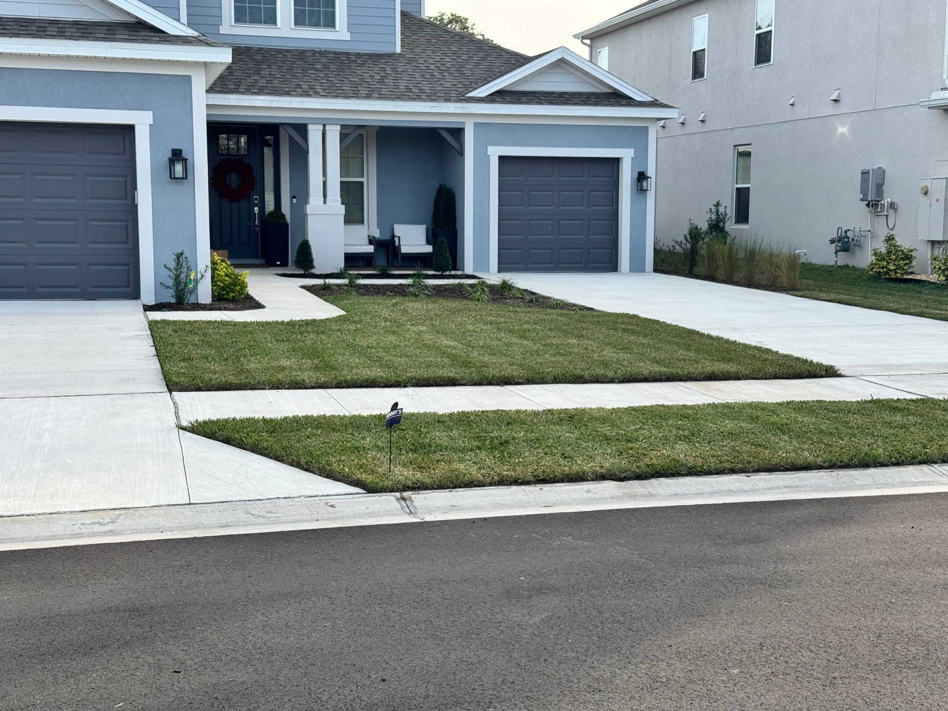 A house with two garages and a lush green lawn