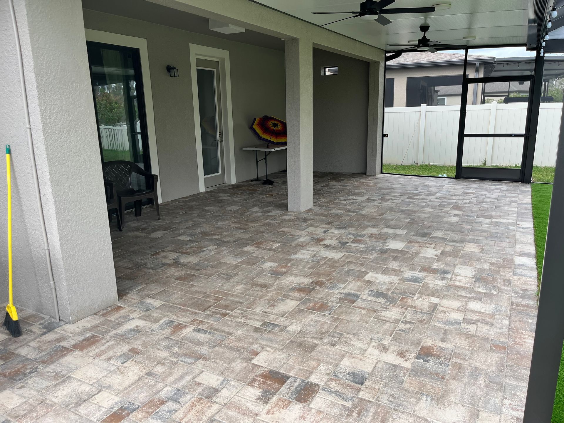 A large patio with a screened in porch and a ceiling fan.