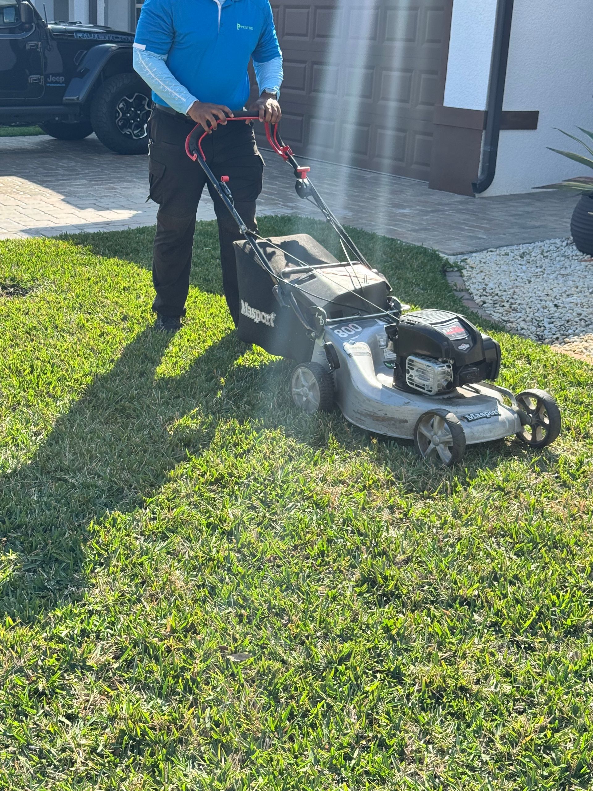 A man is cutting the grass with a lawn mower.