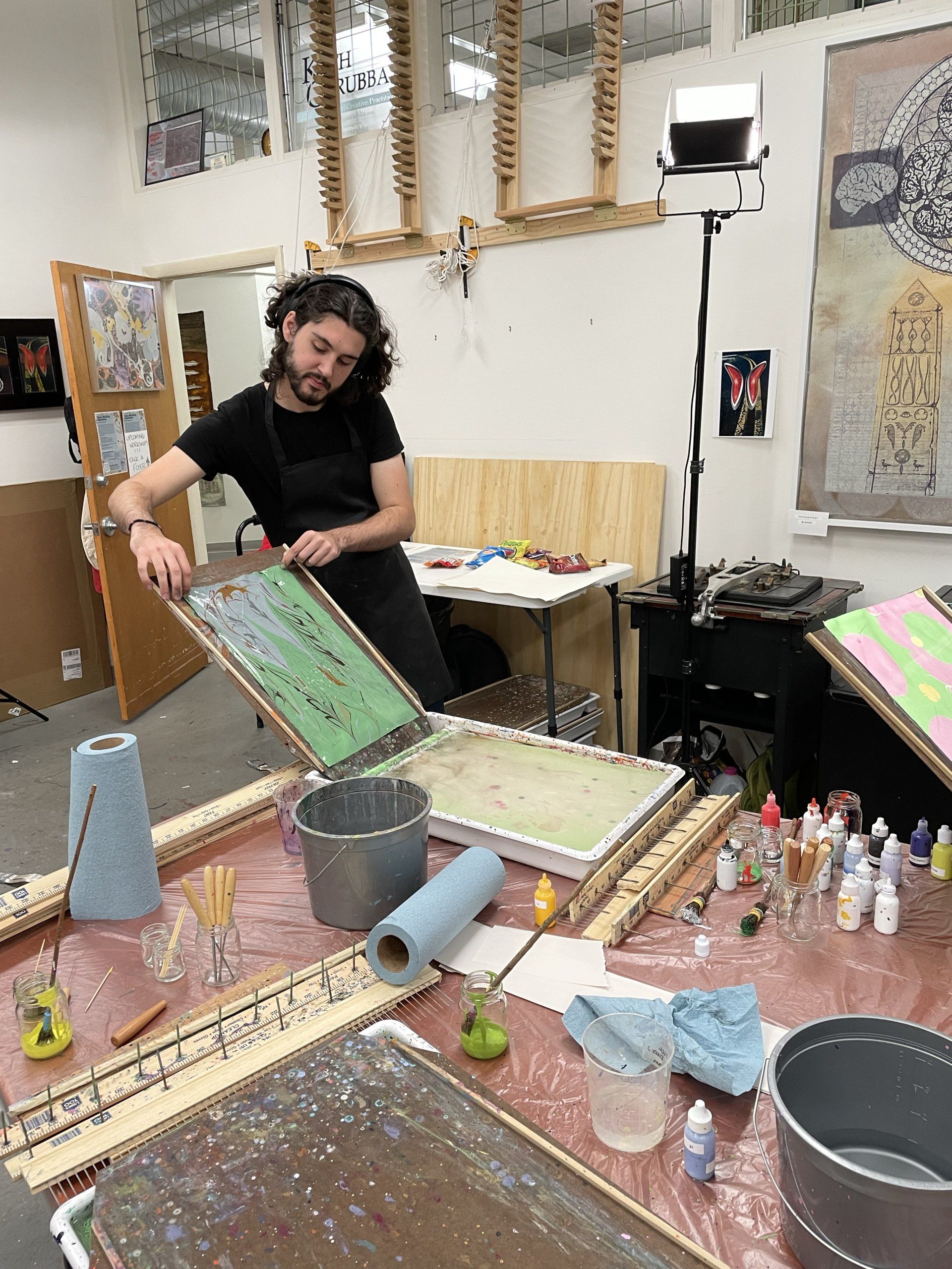 Young Man pulls his dripping print from the bath and admires his artwork.