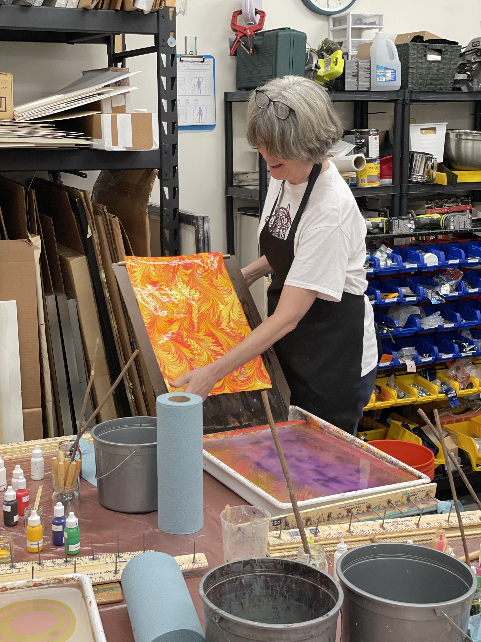 Woman lays her freshly marbled print out on her rinse board.