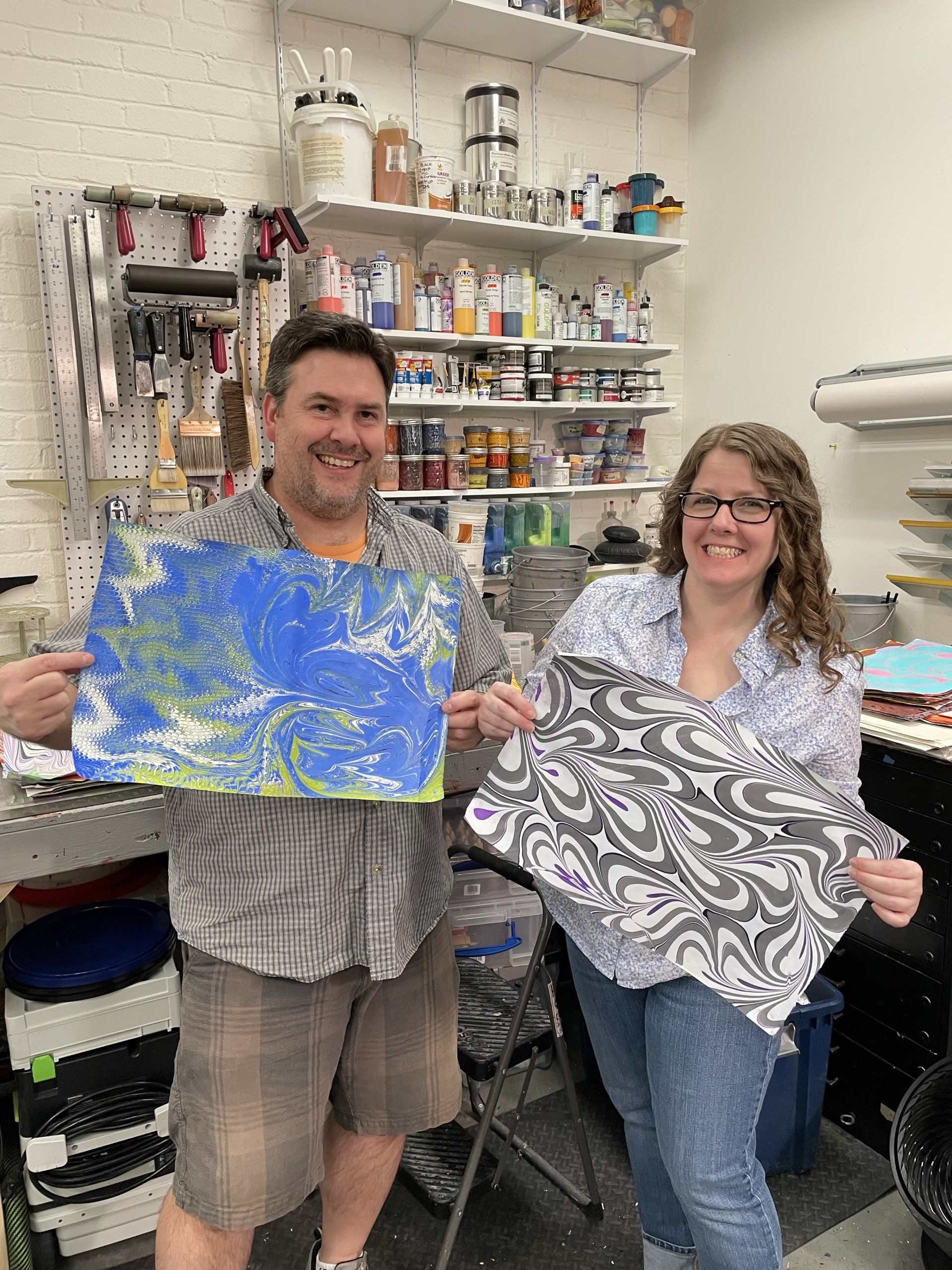 A couple each holds their own marbled creations, freshly produced at Garubba's Paper Marbling Experience.