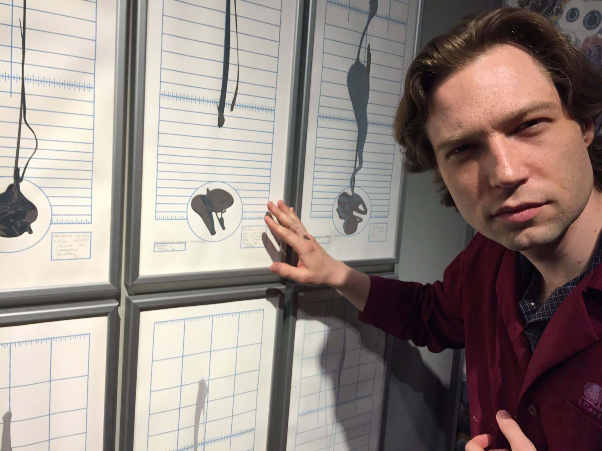 Garubba poses as a Dr. Armbruster intern in a performance interaction with his works on paper.  He looks to the camera with intense gaze.