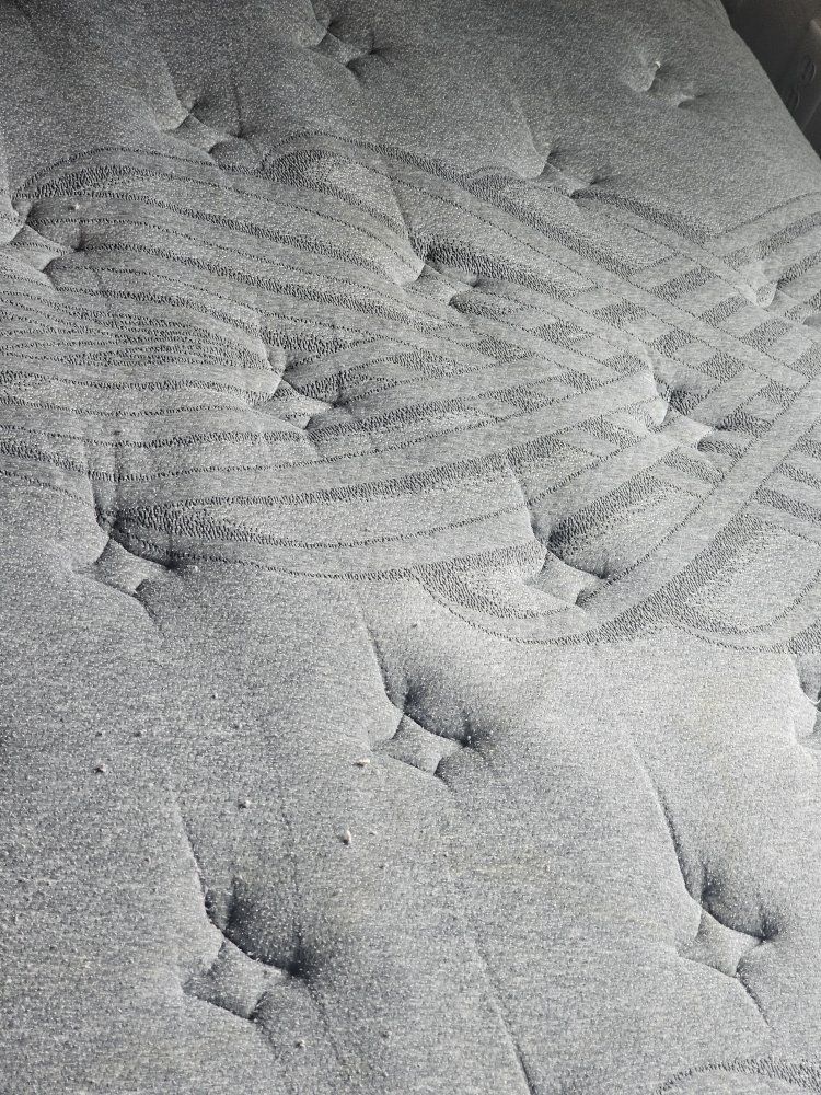 Gray mattress with dark marks, likely from use.