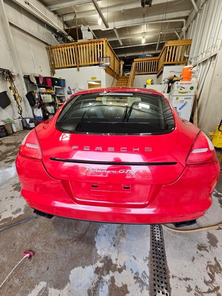 Red Porsche Panamera parked inside a garage.