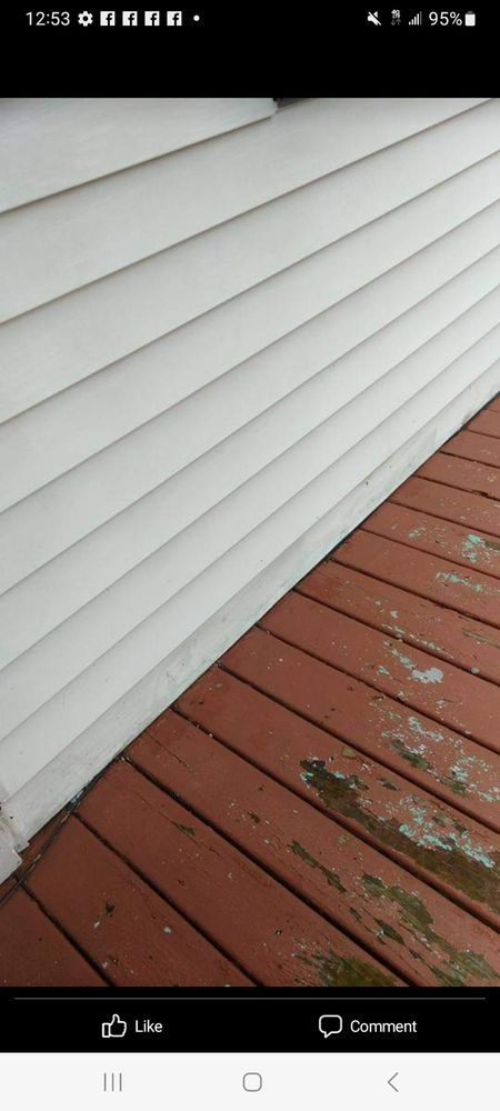 White siding next to a red wooden deck with some green algae.