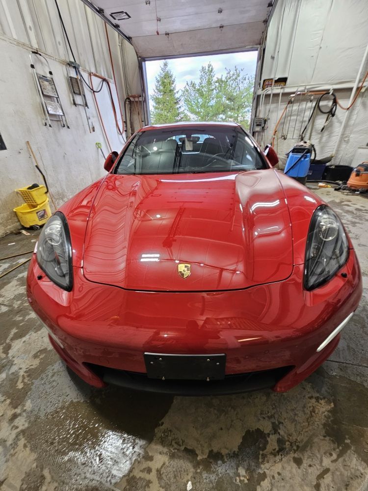 Red Porsche Panamera in a car wash bay.