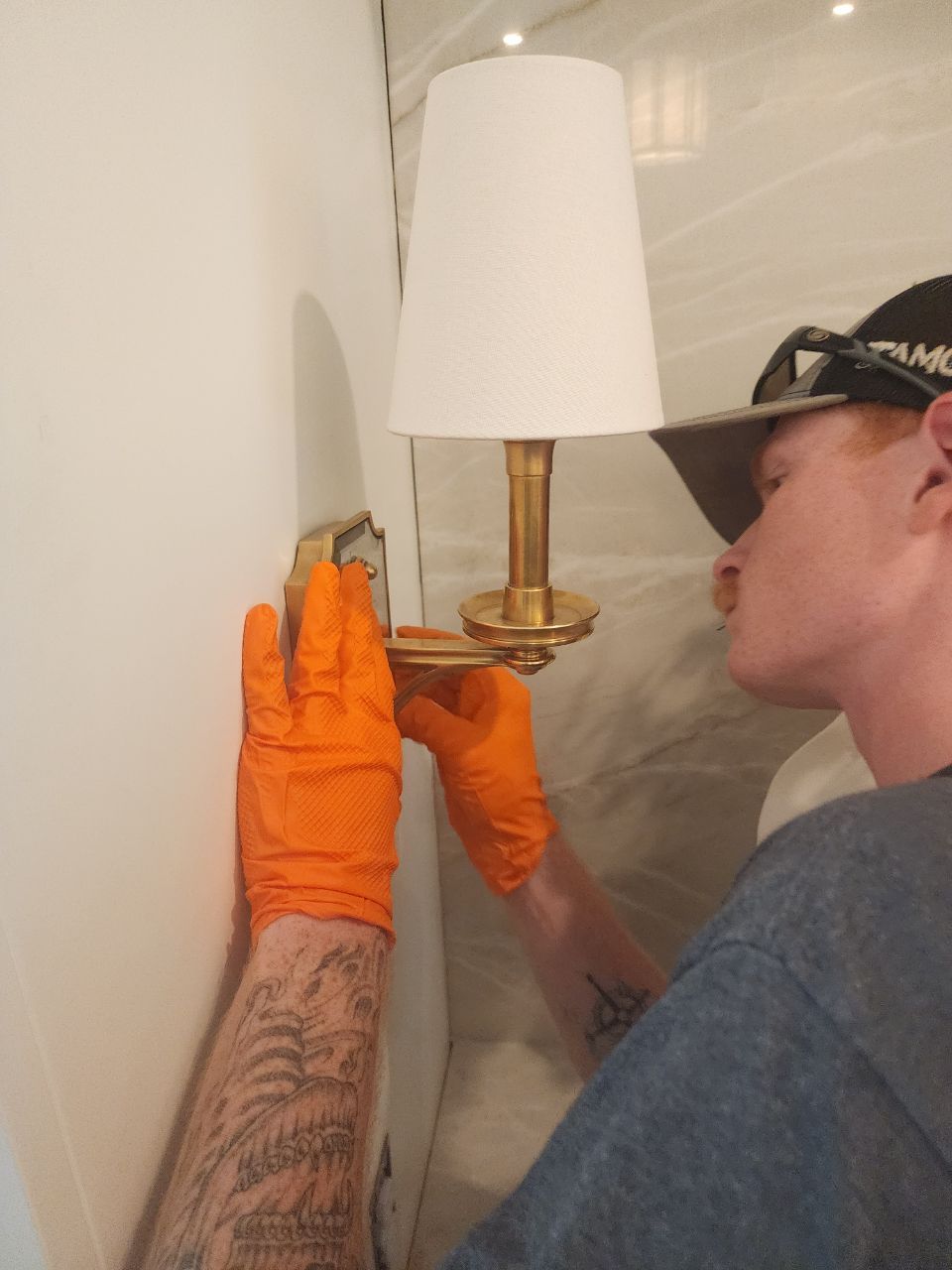 Man in blue jumpsuit and gloves operating machinery control panel.