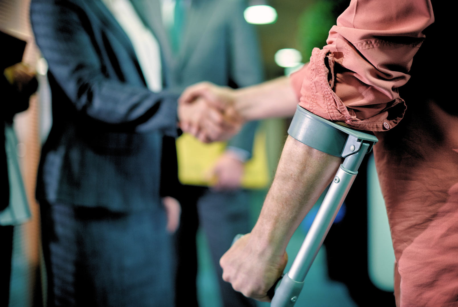 A man with crutches is shaking hands with a woman.