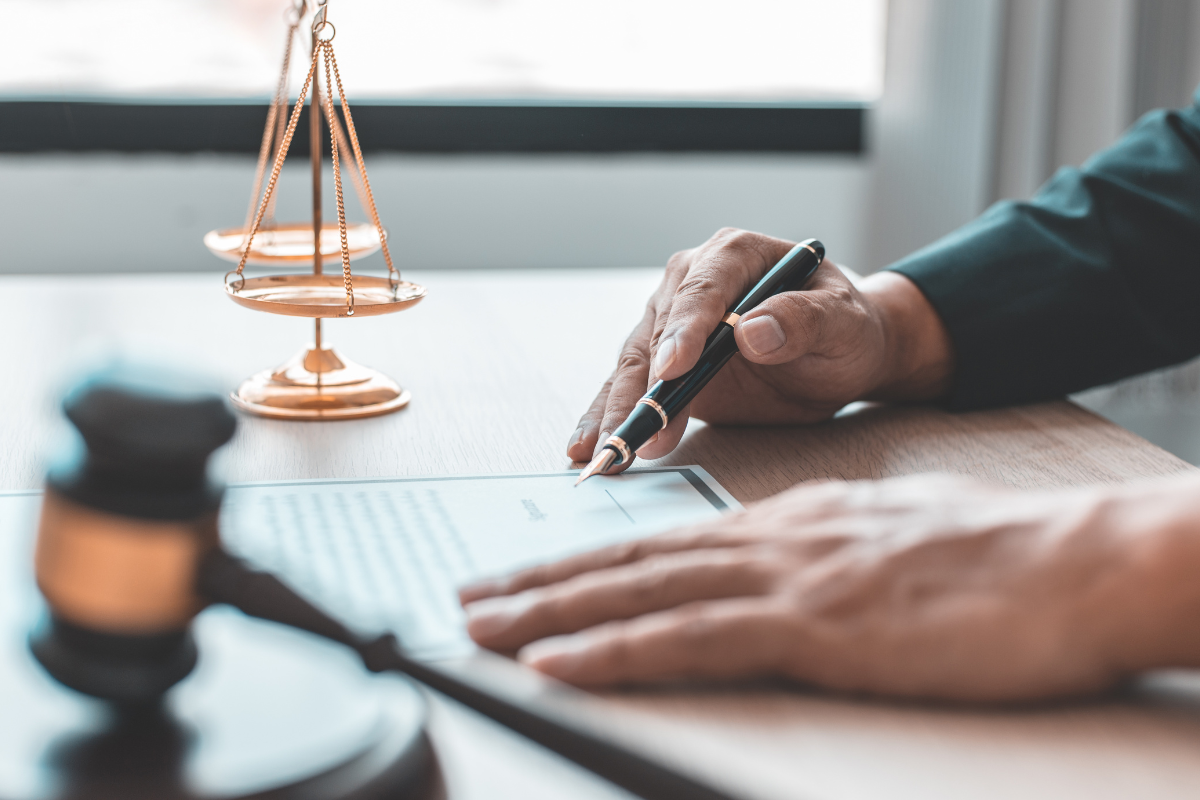 A person is sitting at a table signing a document with a pen.