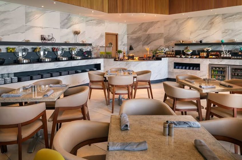 Elegant restaurant dining area with buffet stations, marble accents, and beige seating.