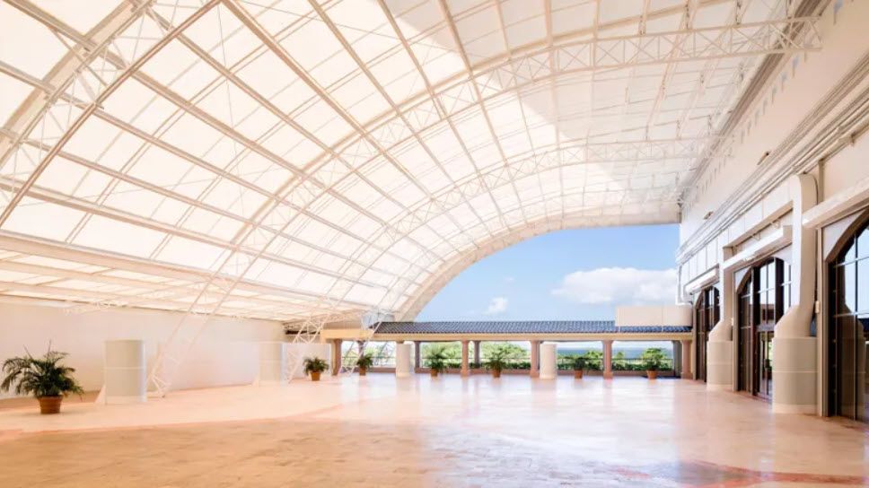 Bright open interior space with arched, translucent ceiling and a view of blue sky.