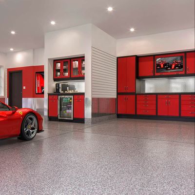 Red sports car parked in a luxury garage with red cabinets, stainless steel backsplash, and a television.