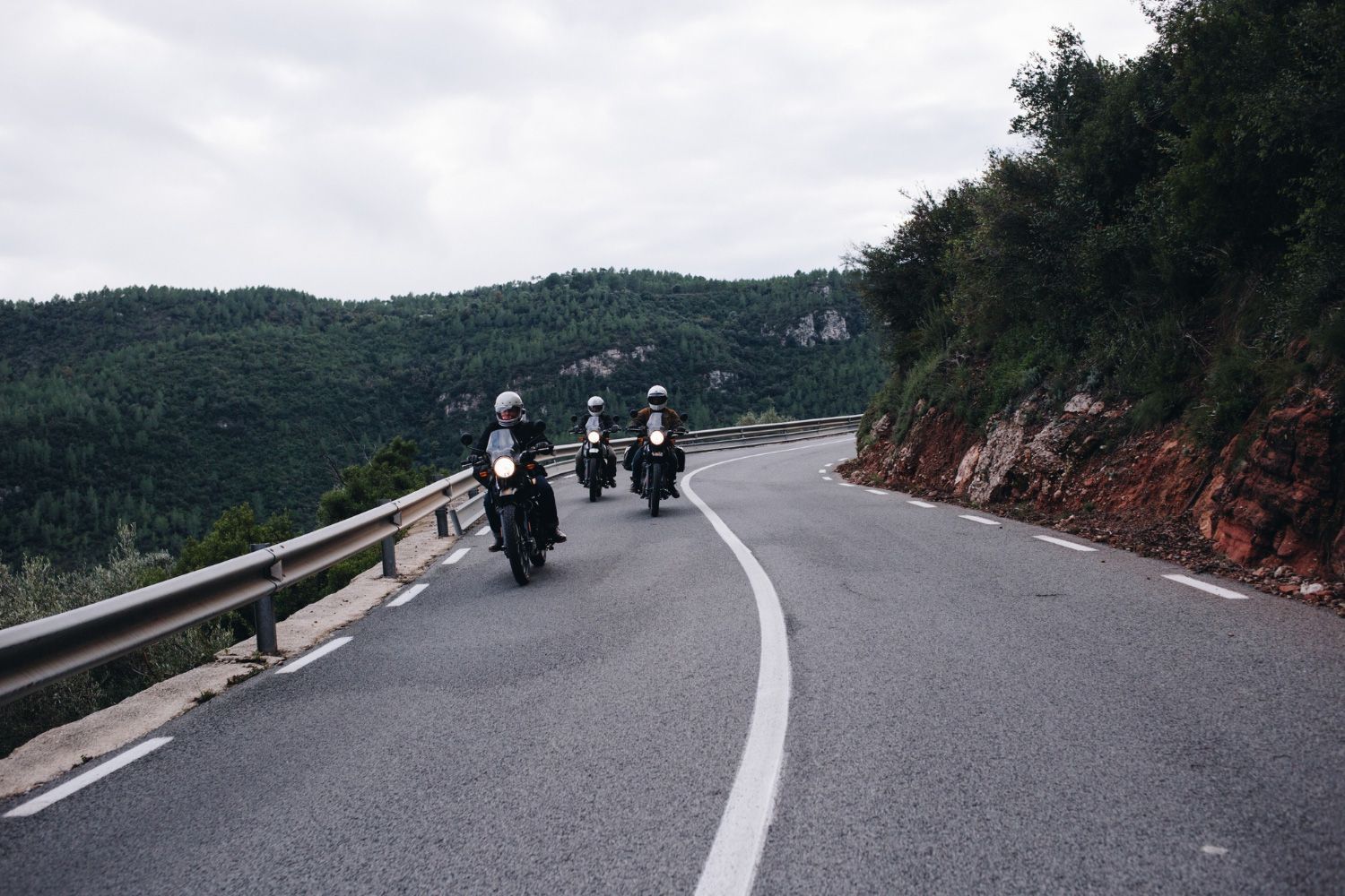 A group of people are riding motorcycles down a curvy road.