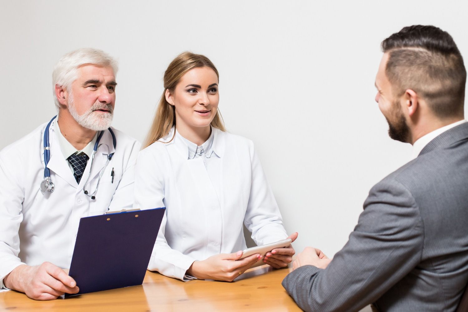 A man is sitting at a table talking to two doctors.