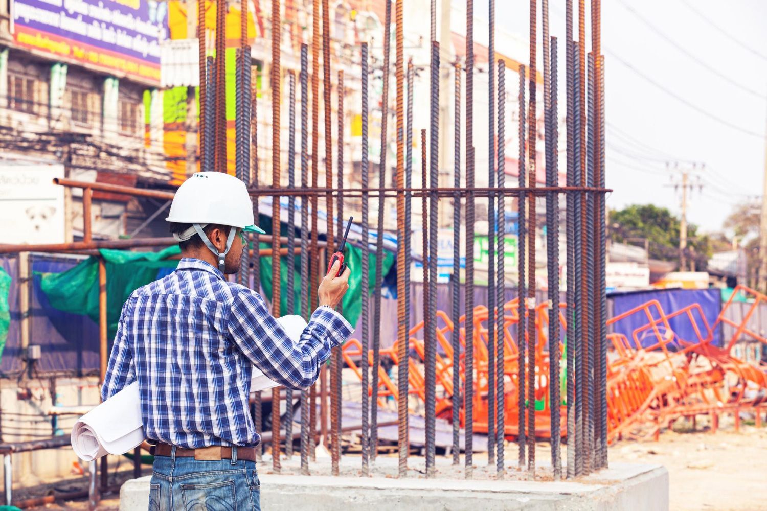 A construction worker is standing in front of a building under construction.
