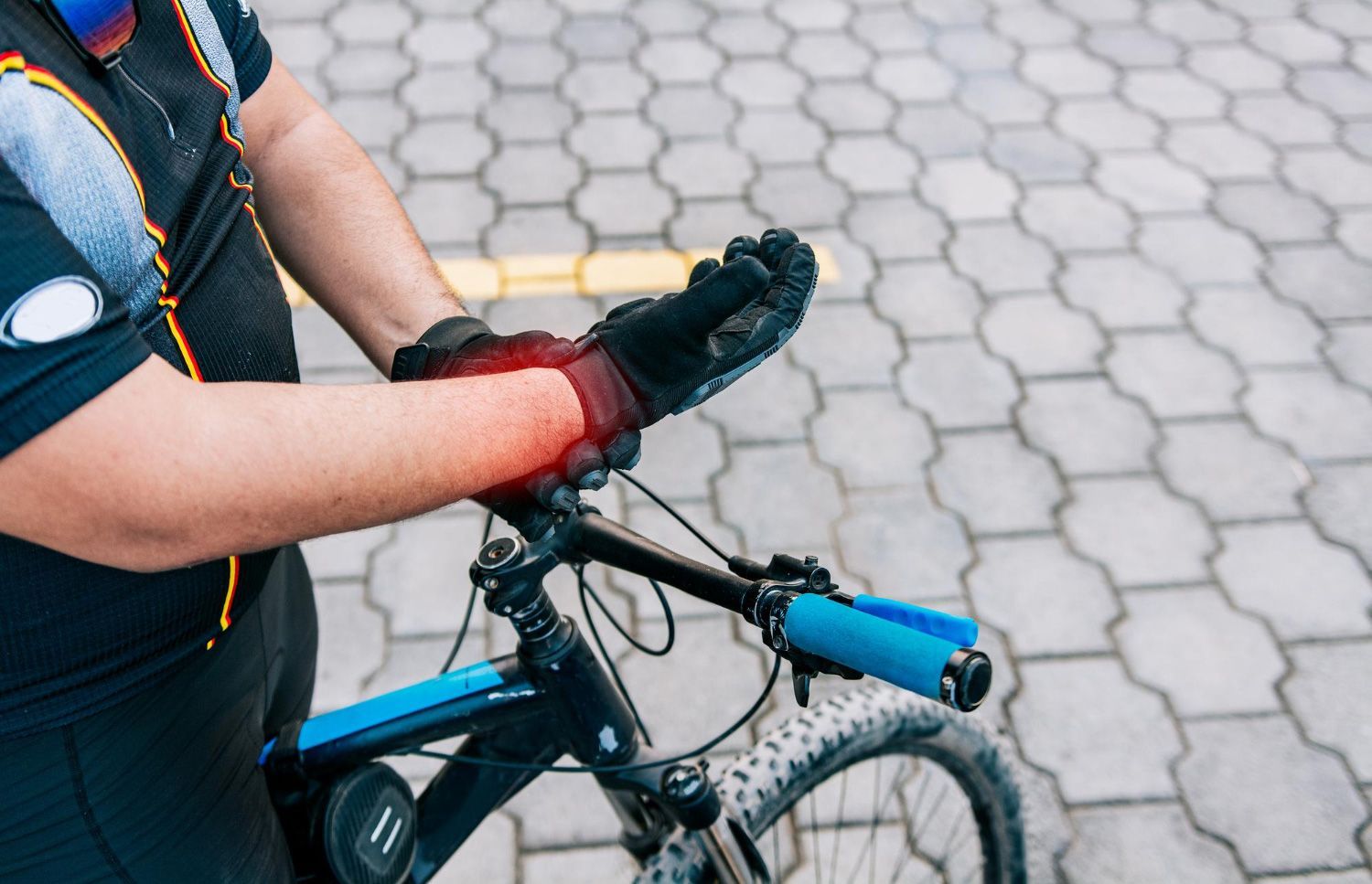 A man wearing gloves is riding a bike on a brick sidewalk.