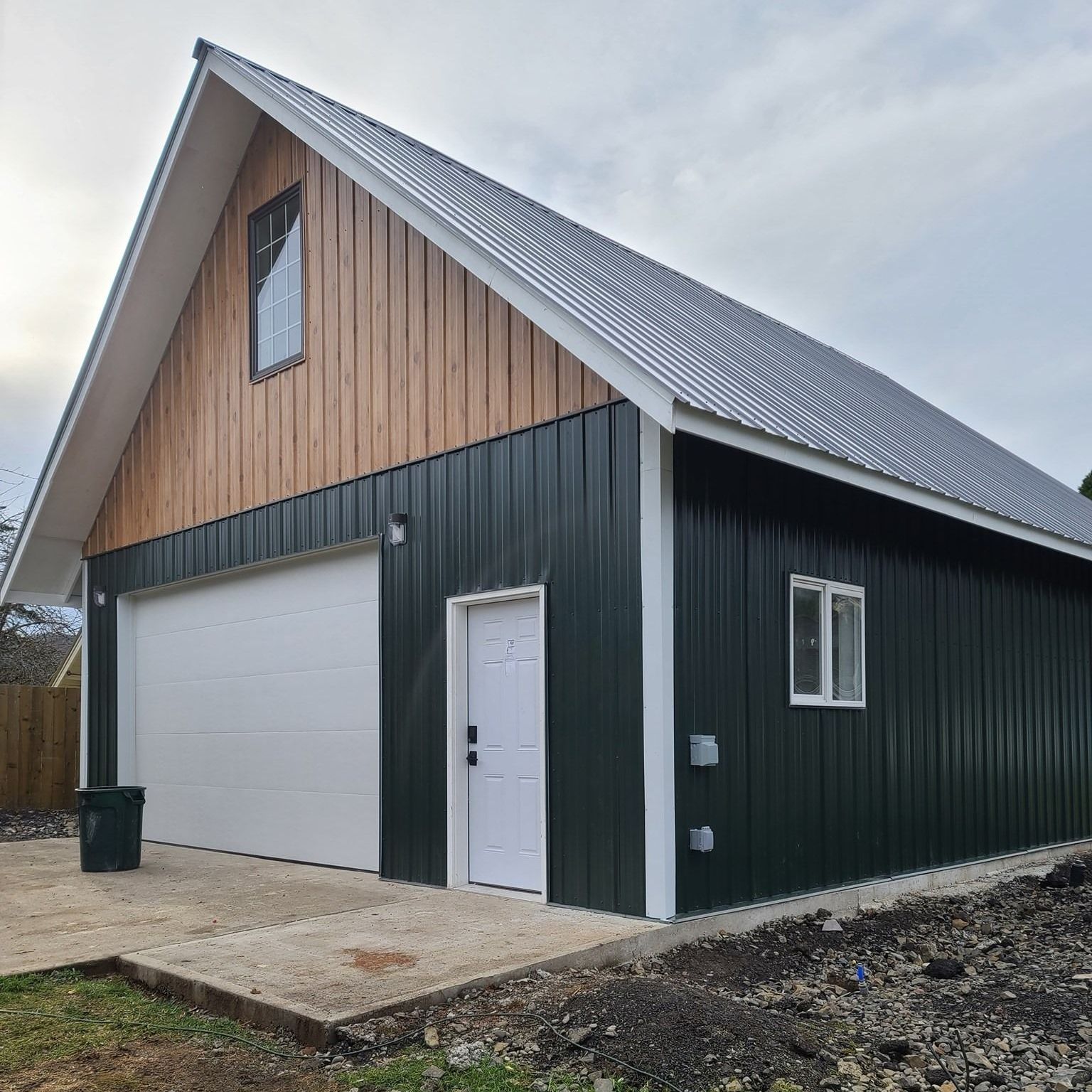 A green garage with a white door and a wooden roof