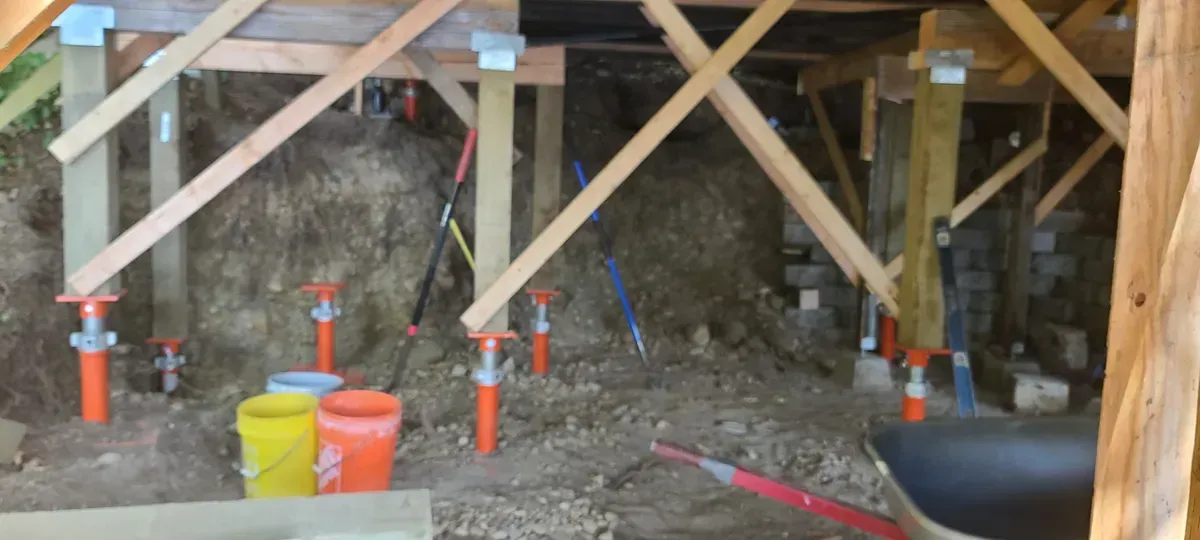 A room with a lot of wooden beams and buckets on the floor.