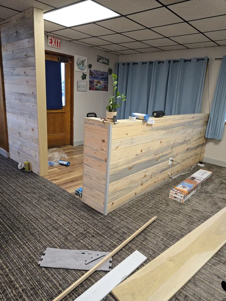 A wooden reception desk is being built in a room.