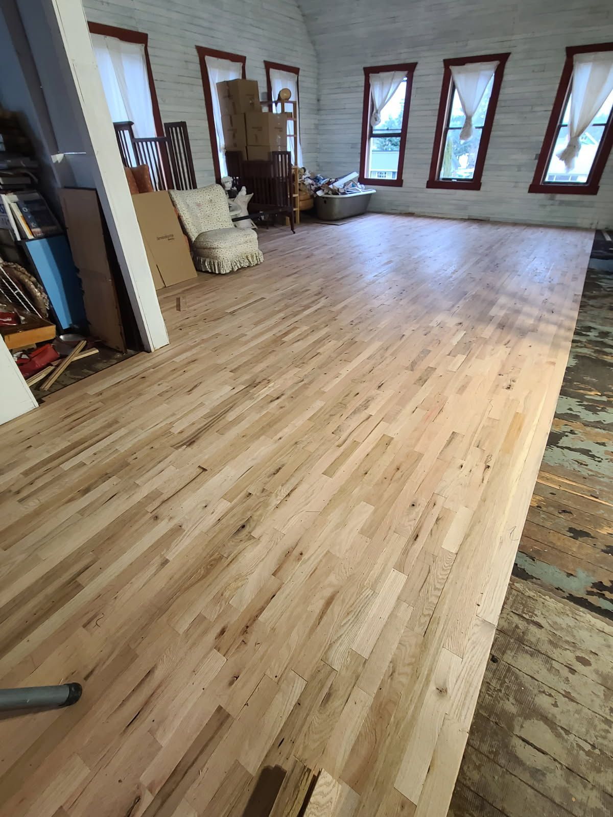 A large room with a wooden floor and lots of windows.