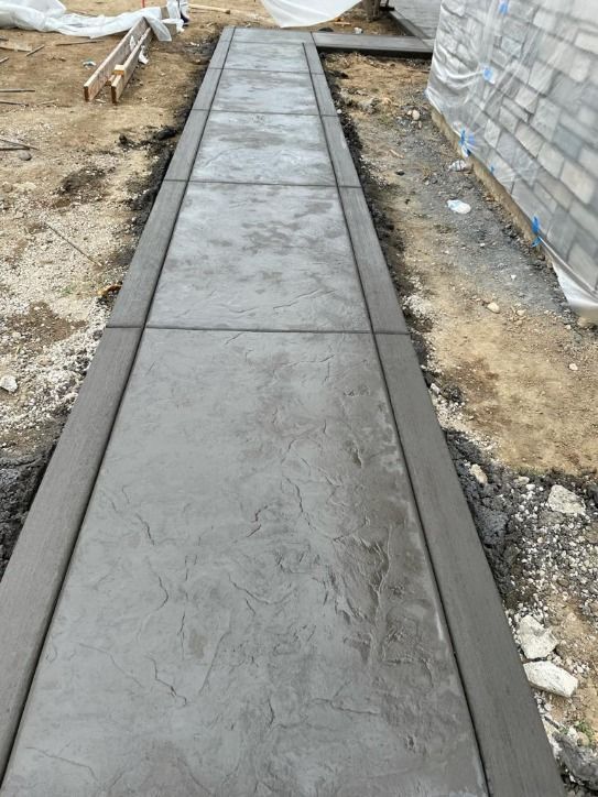 A concrete walkway is being built in front of a brick building.