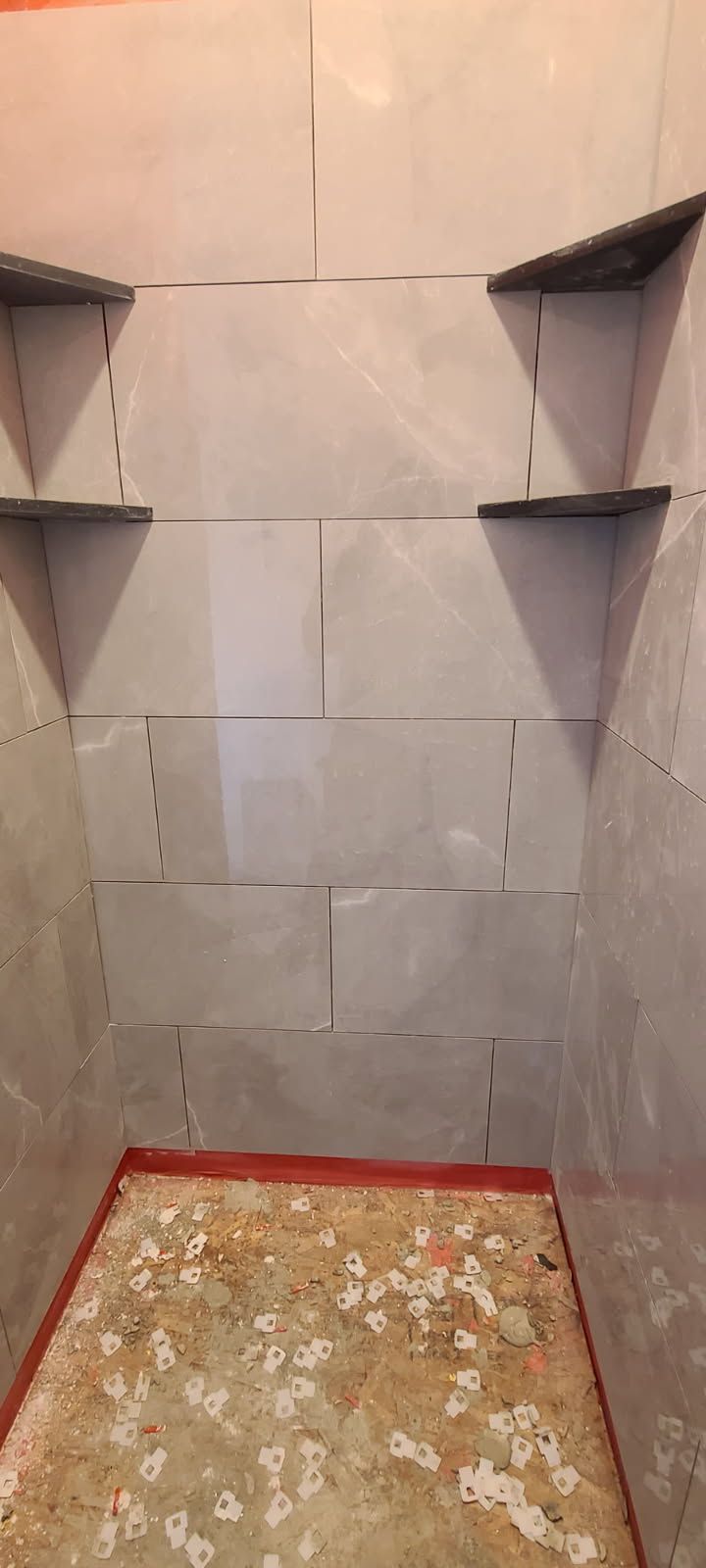 A small room with a tiled wall and shelves.