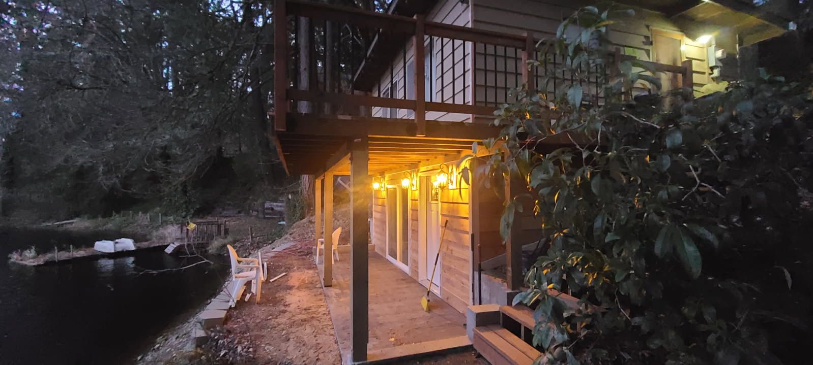 A log cabin with a large porch overlooking a lake at night.