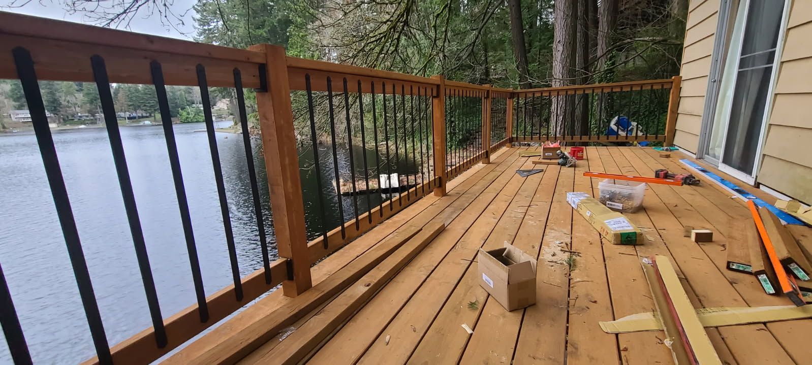 A wooden deck with a metal railing overlooking a body of water.