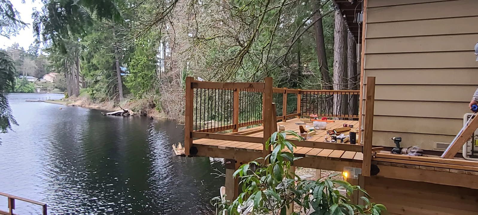 A wooden deck overlooking a lake with trees in the background.