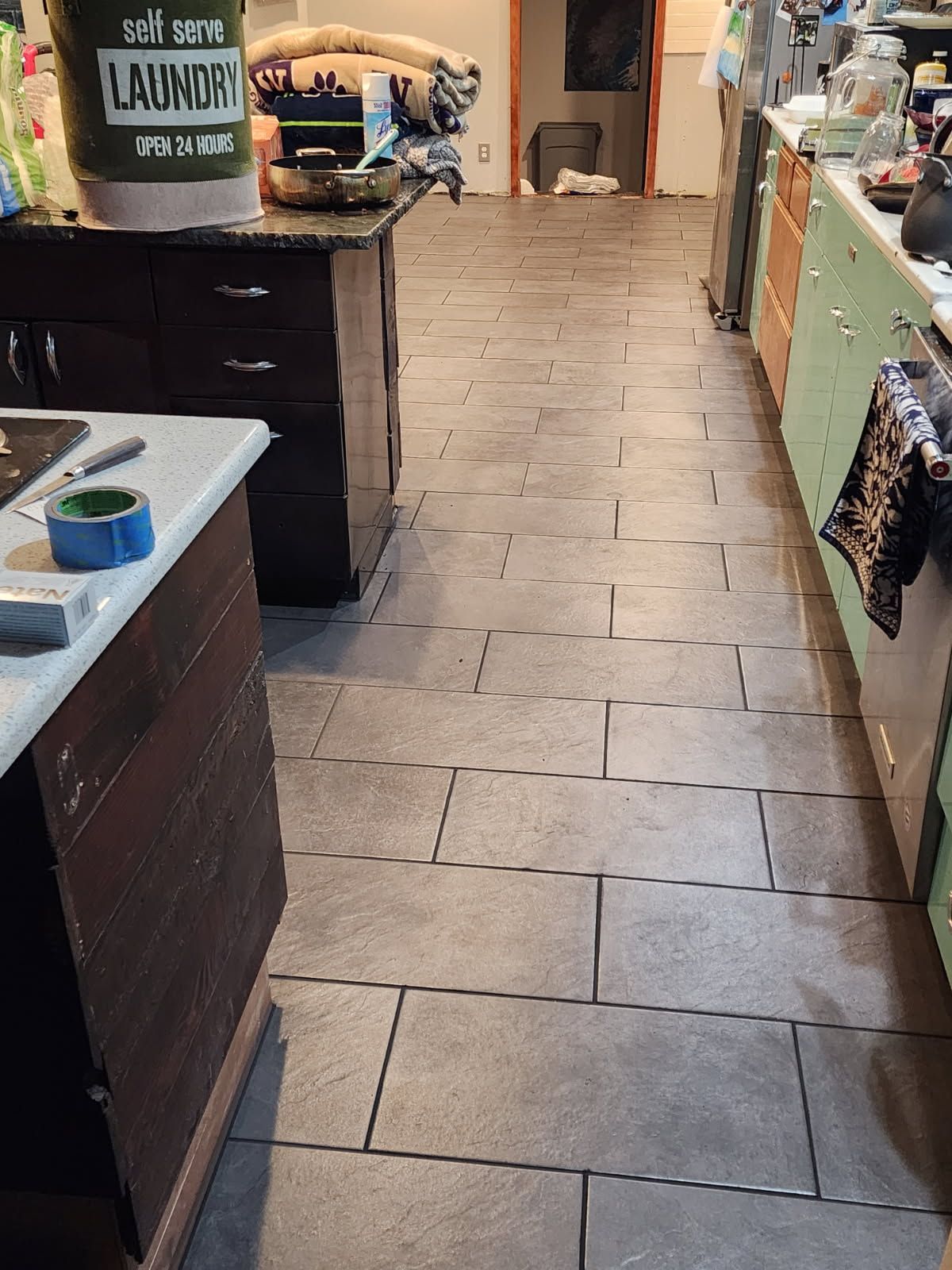 A kitchen with a bucket of laundry on the counter.
