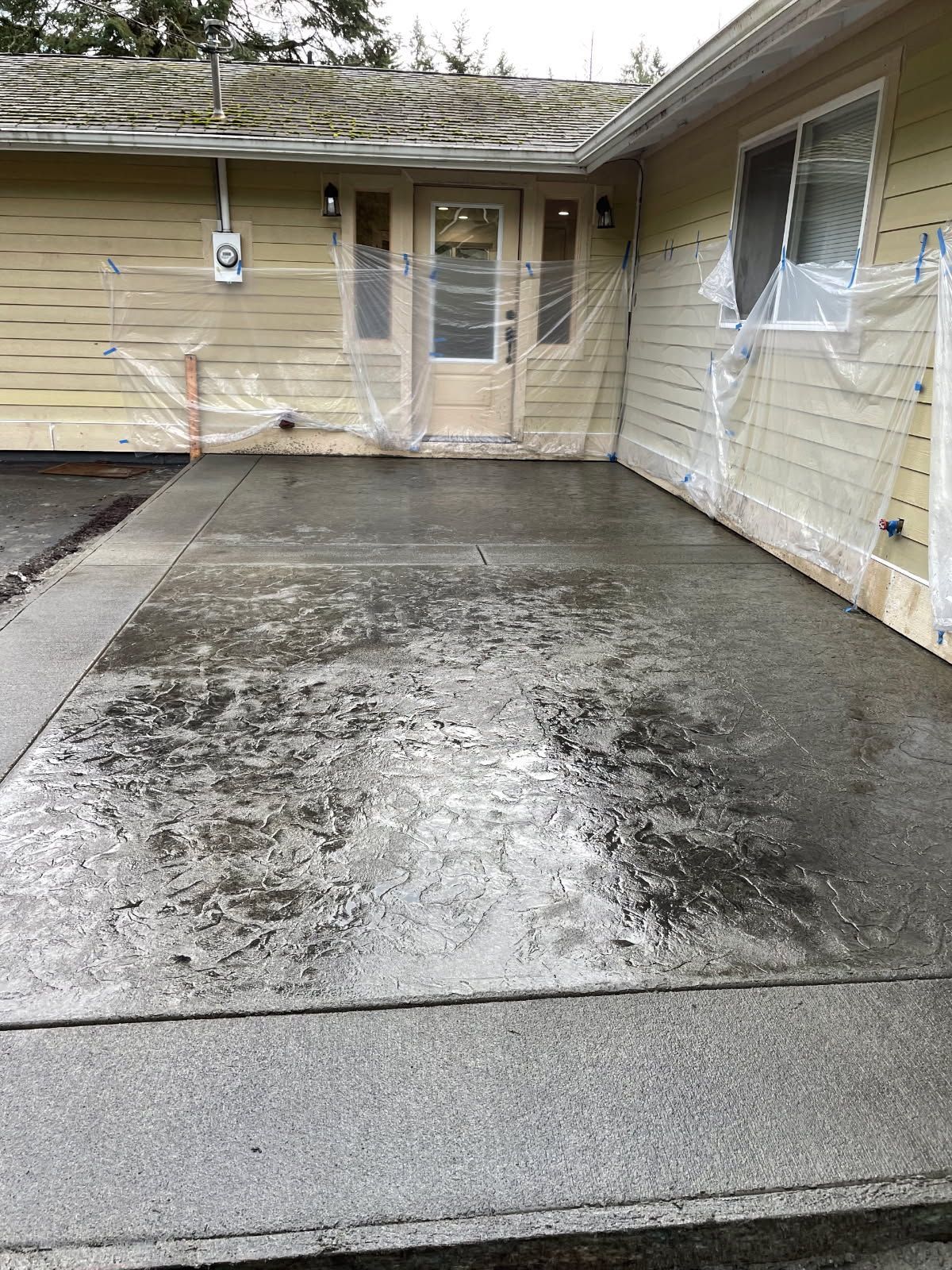 A dirty concrete driveway in front of a house.