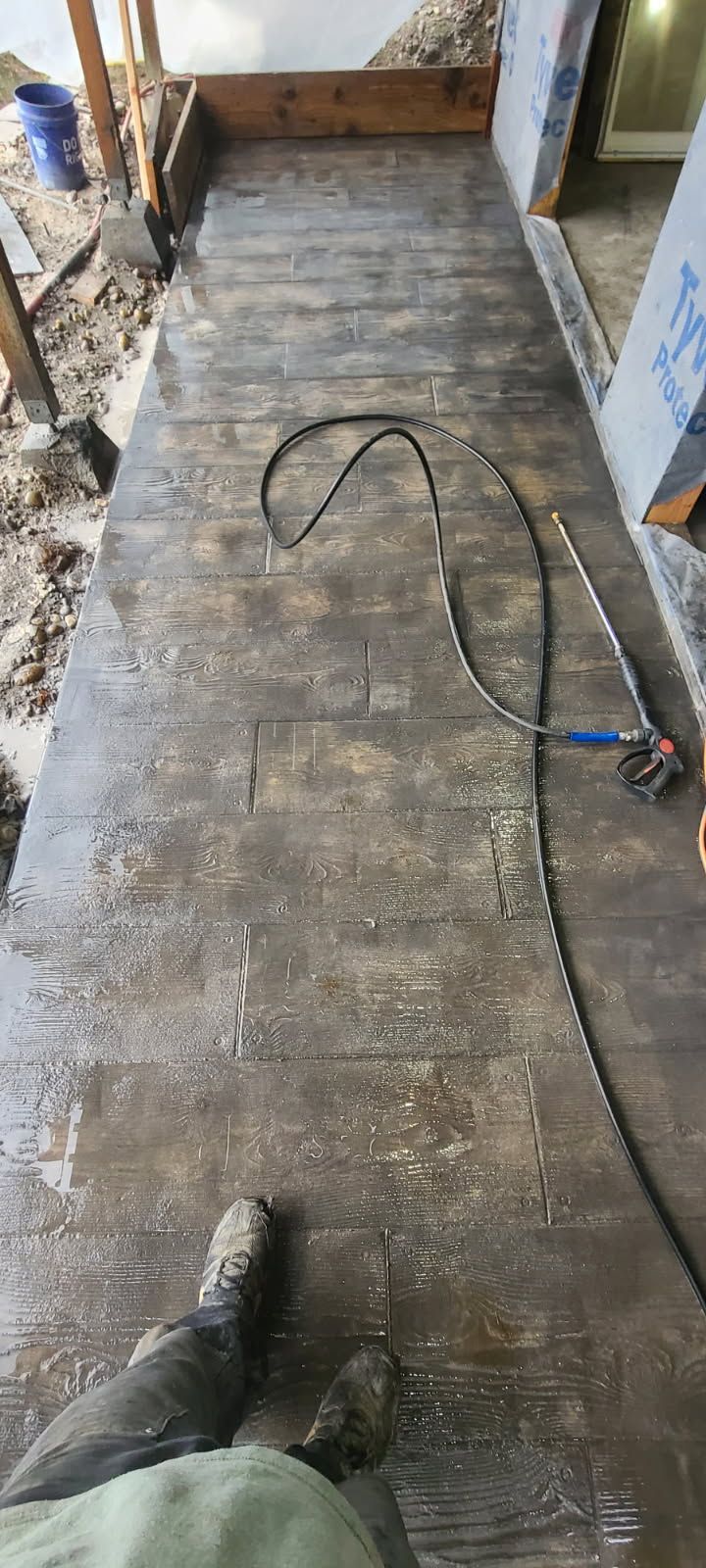 A person is standing on a concrete floor next to a hose.