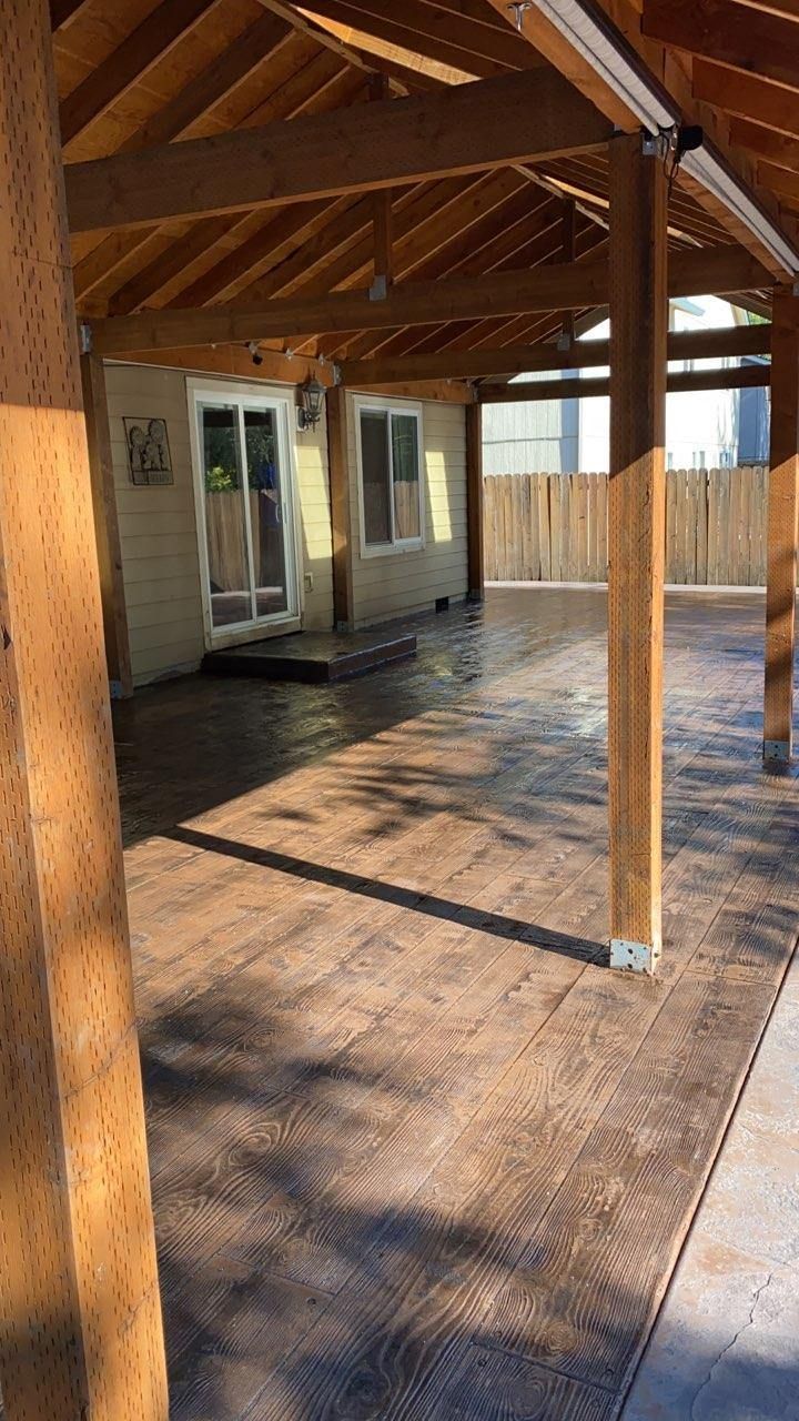 A covered patio with a wooden roof and a concrete floor.