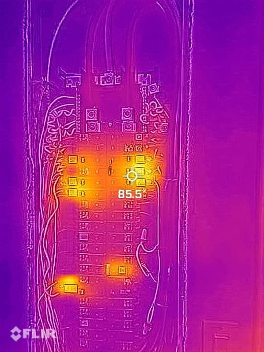 Thermal image of an electrical panel. Hot spots are orange/yellow, reaching 85.5 degrees. Purple background.