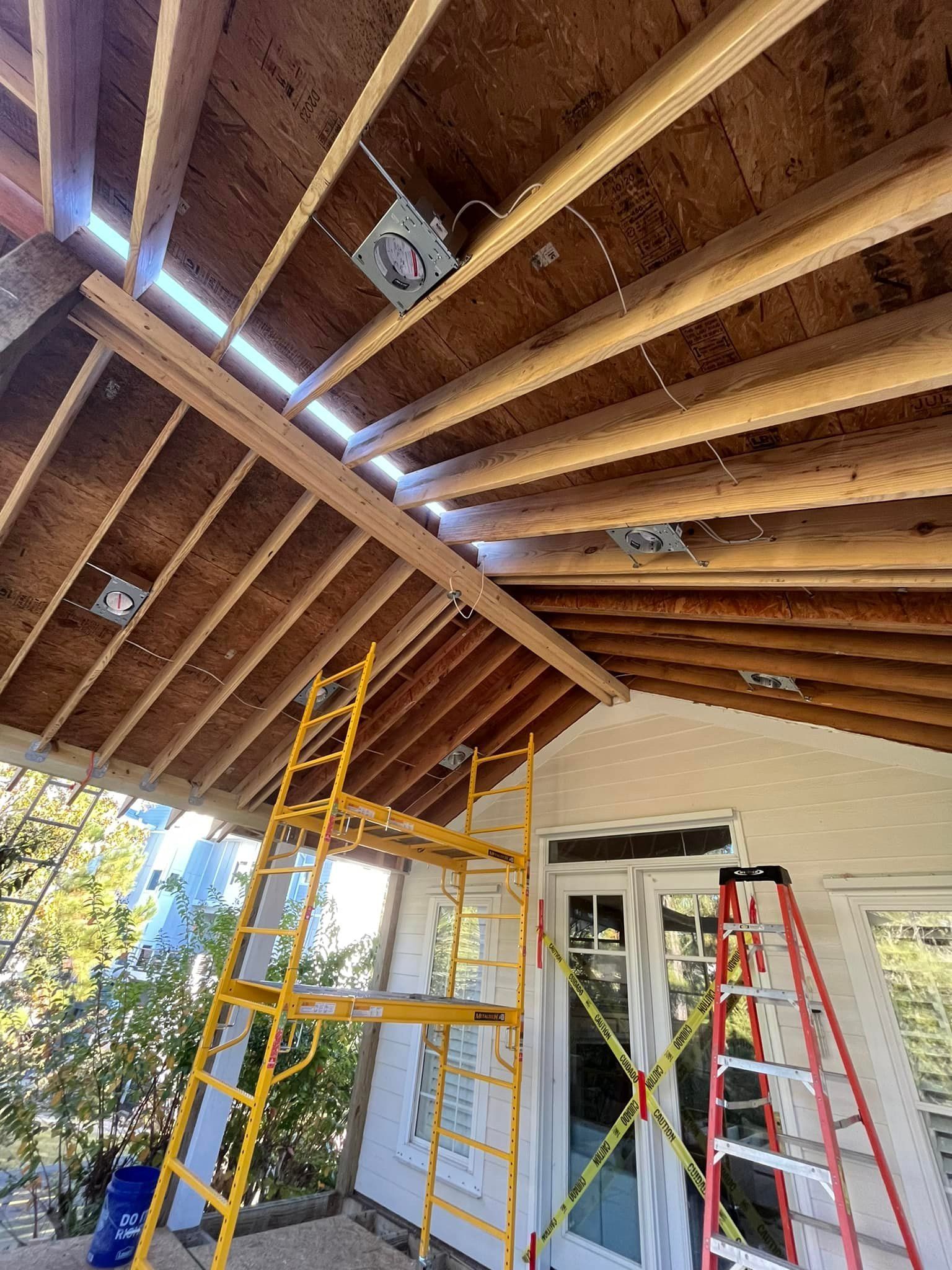 Construction scene: exposed wooden ceiling beams with installed electrical boxes, scaffolding.