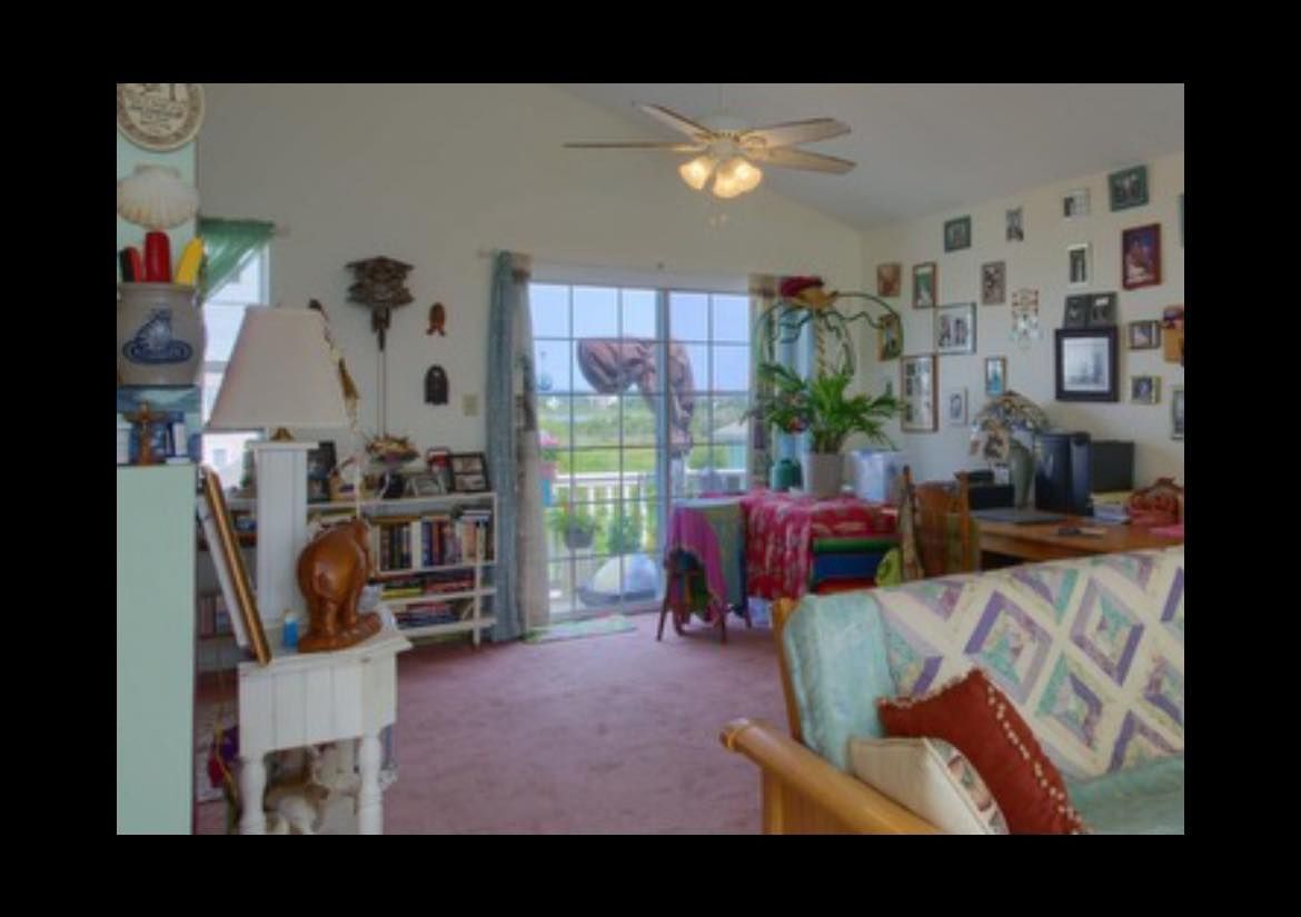 Cozy living room with a view; red carpet, books, artwork, and a sliding glass door.