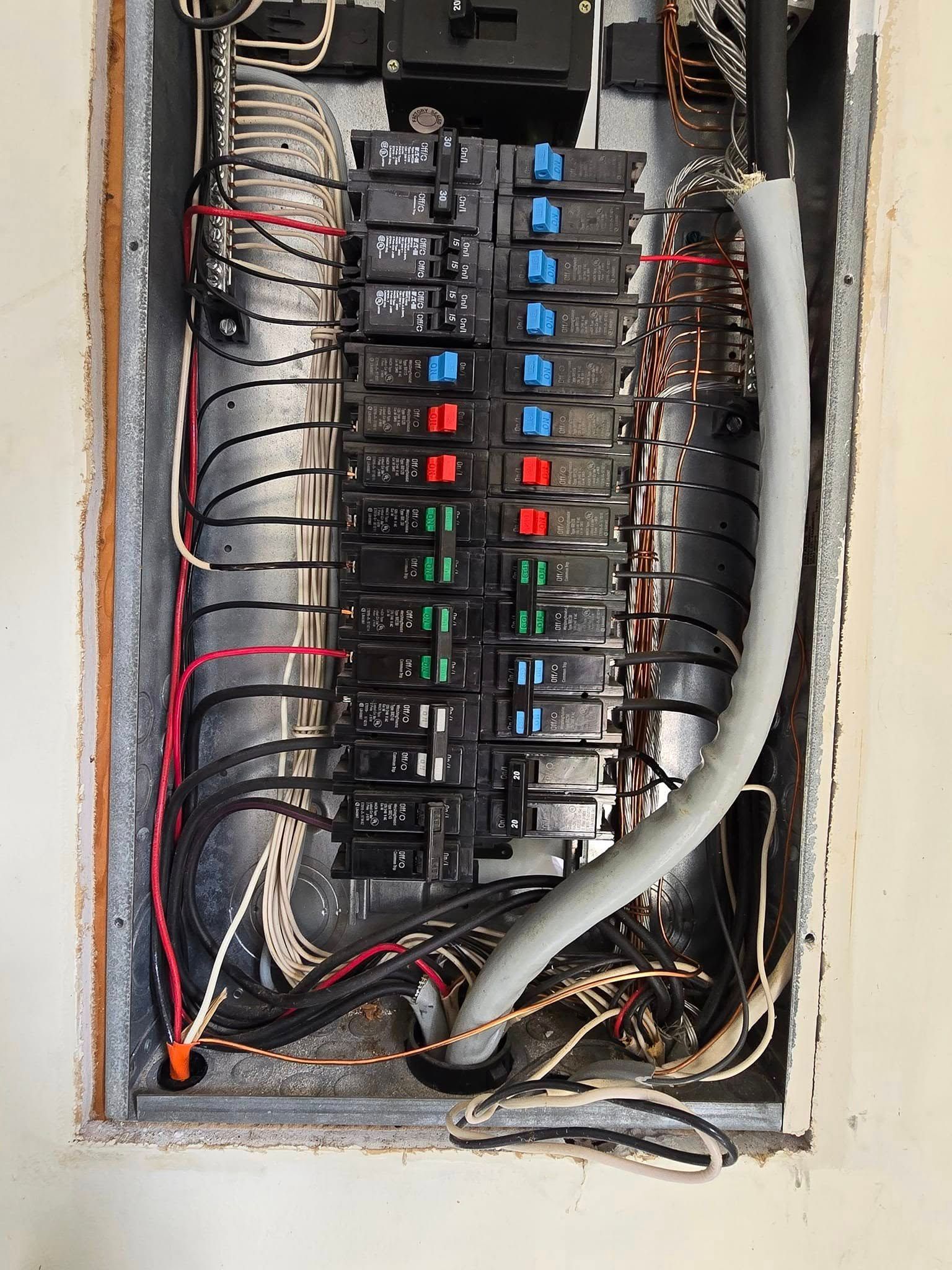 Electrical circuit breaker panel with numerous colored and black wires.