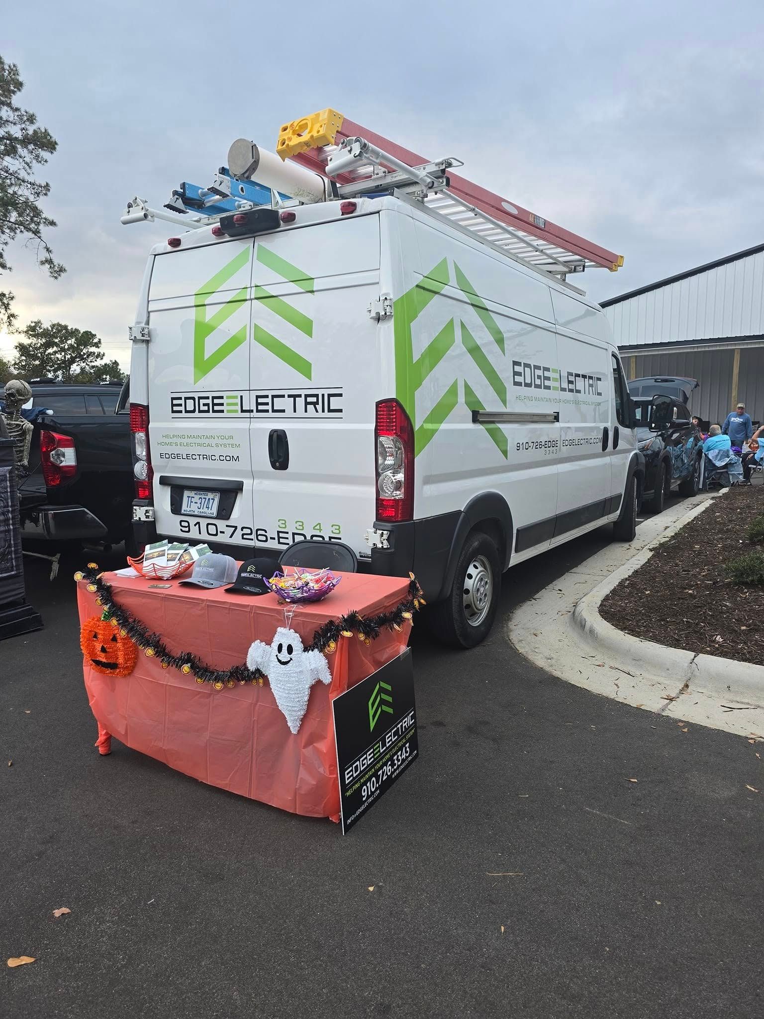 White Edge Electric van with Halloween candy table in front.