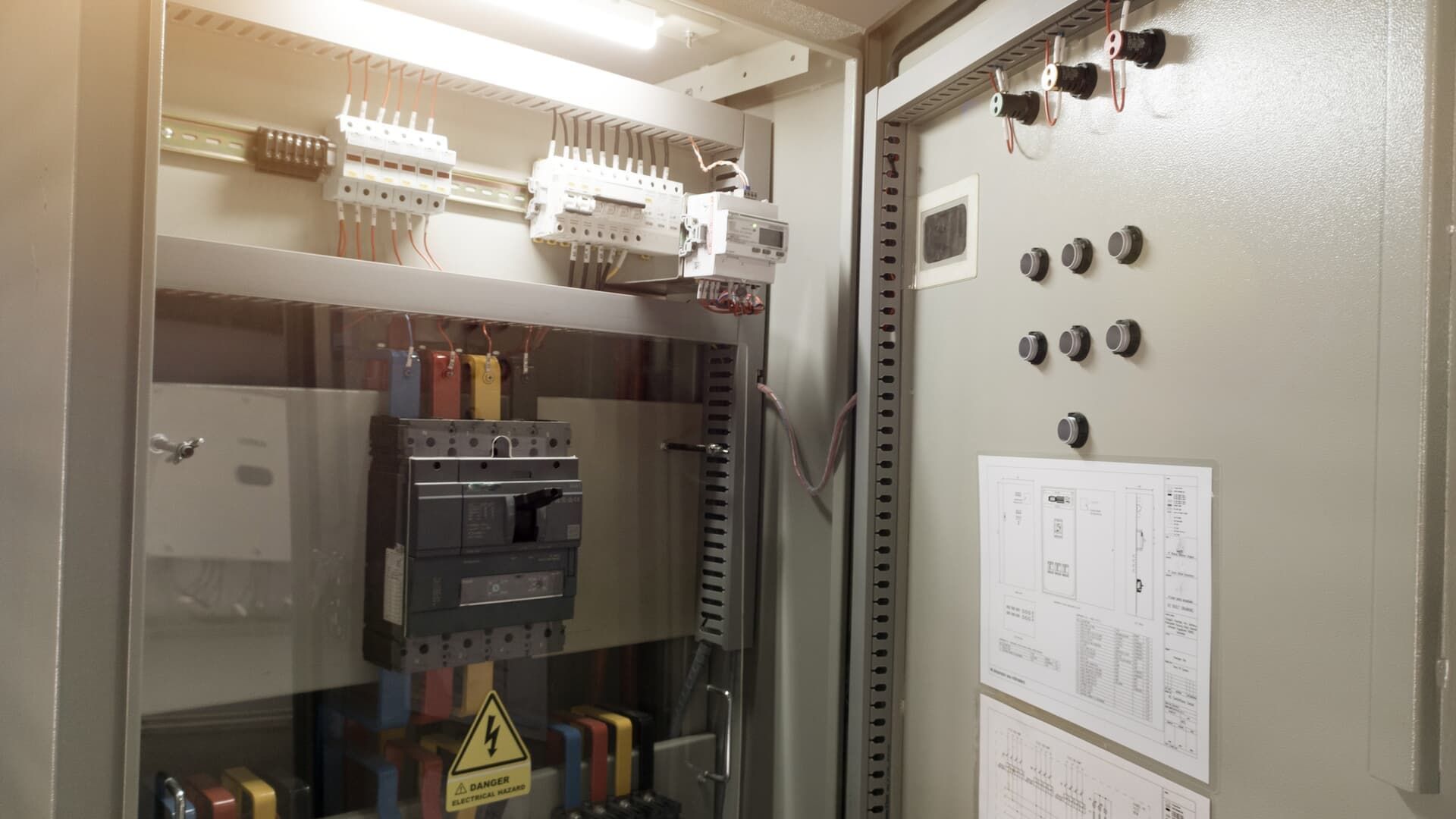 Open electrical panel with various components, including breakers and wiring, with a schematic on the door.