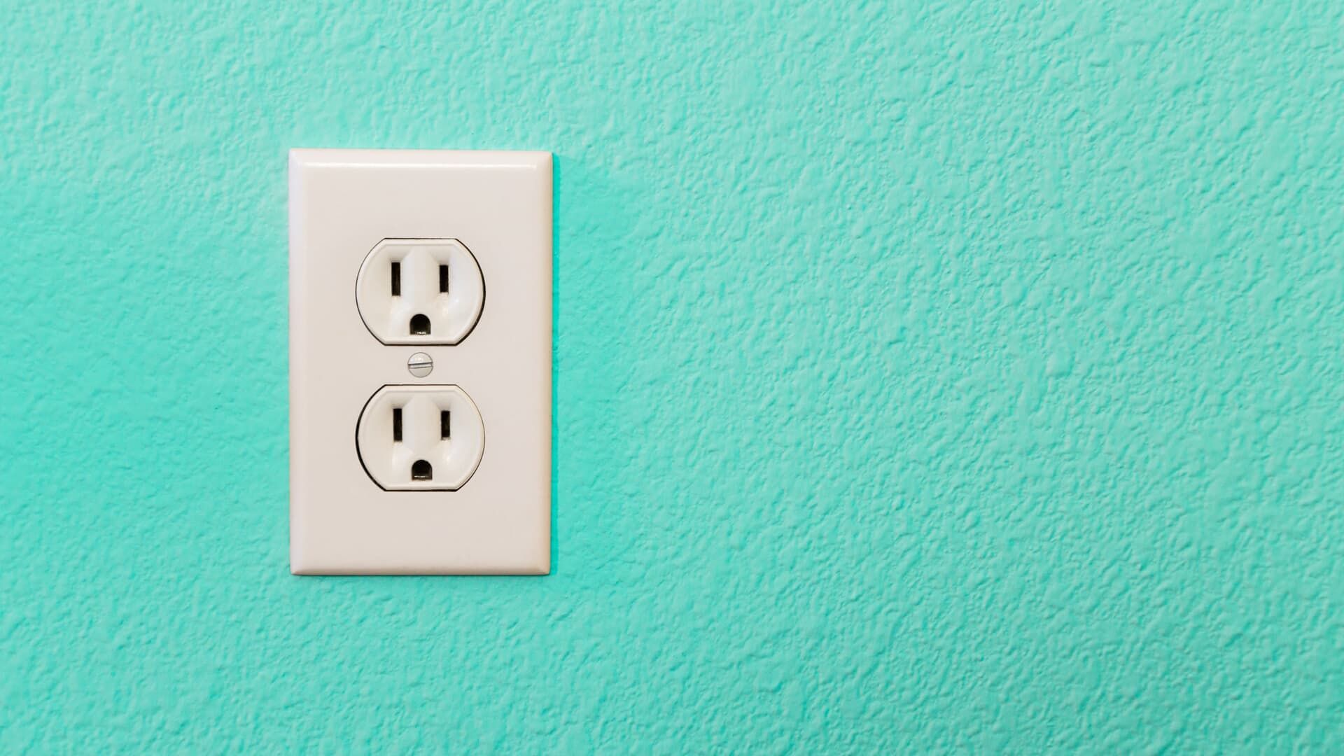 White electrical outlet on a teal wall.