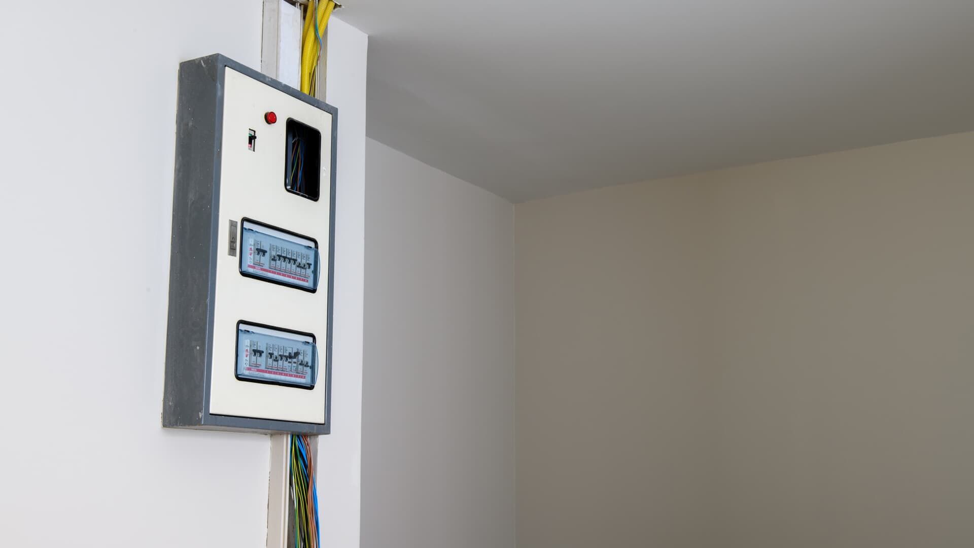 Electrical panel on a white wall with wiring.