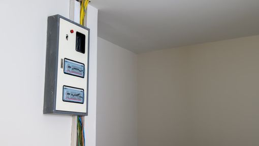 Electrical panel mounted on a white wall, with wiring.