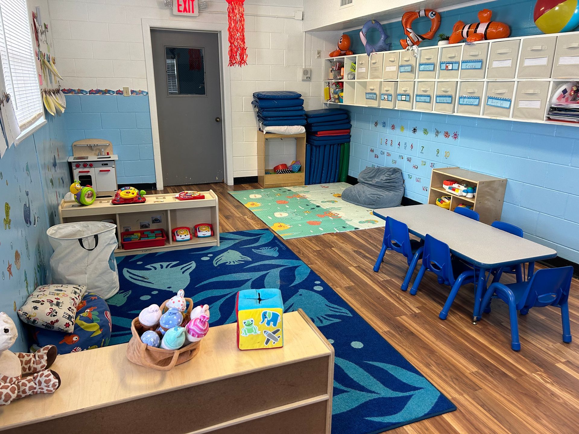A classroom with tables and chairs and toys on the floor.