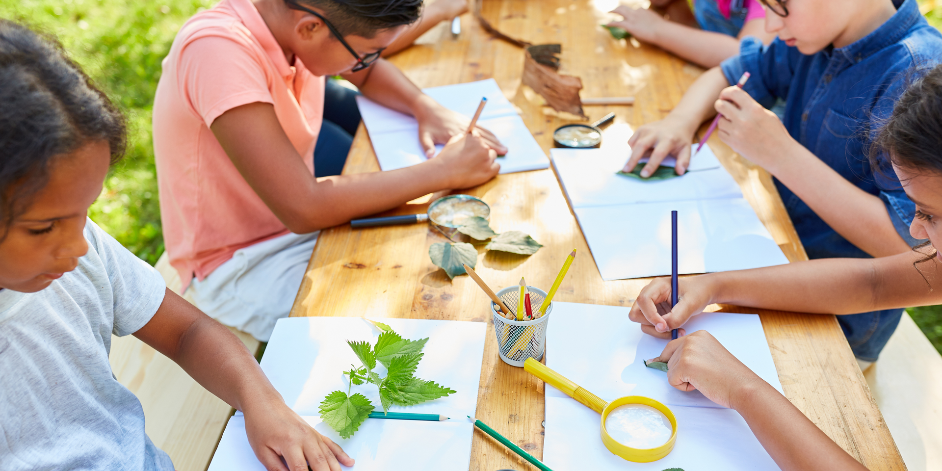 A group of children are sitting at a table drawing.
