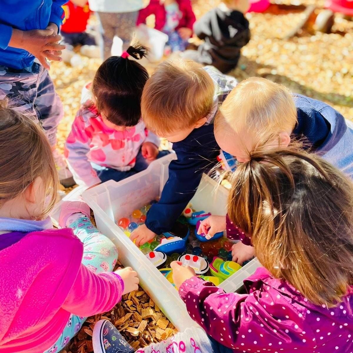 A group of children are playing with toys in a bin.