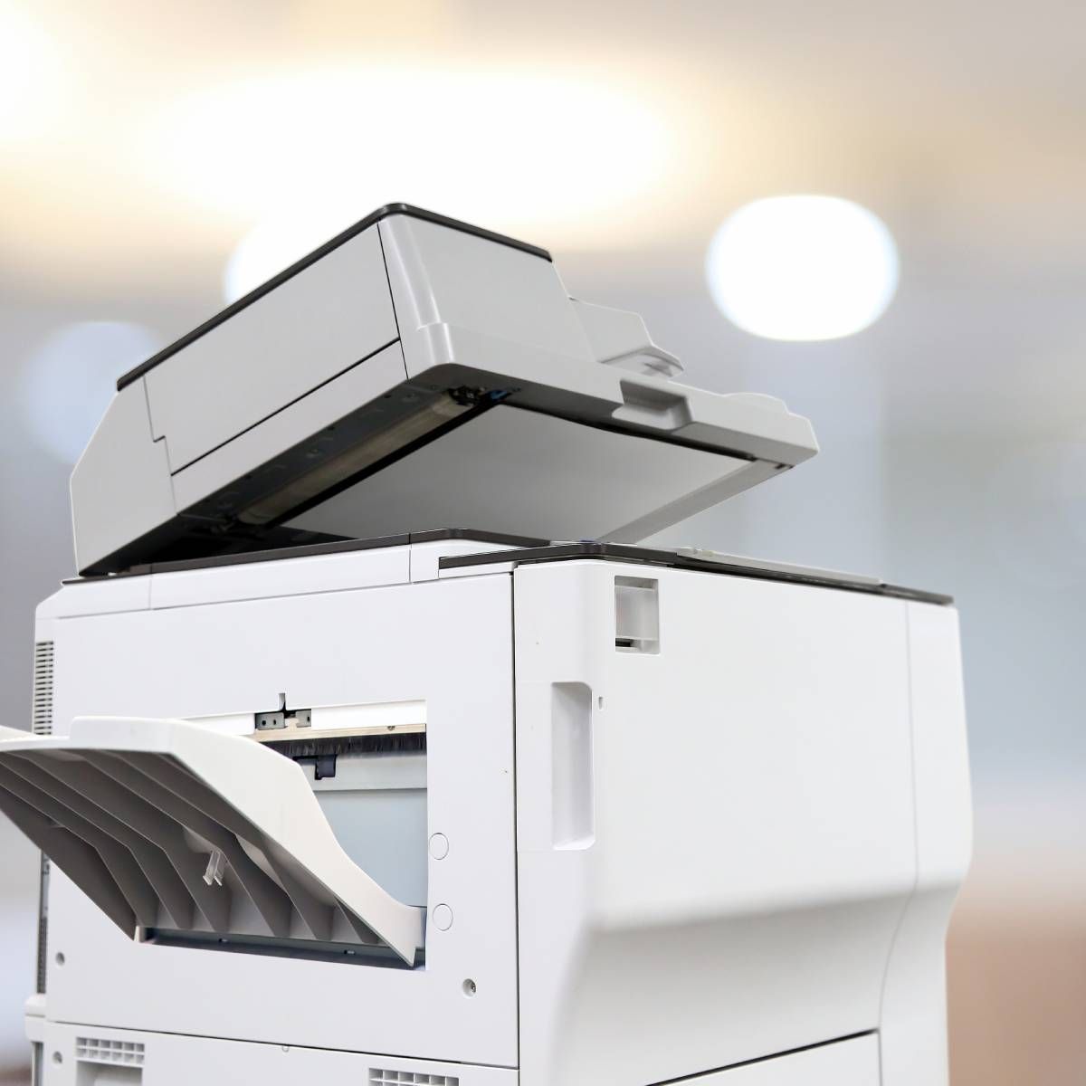 A white printer with the lid open is sitting in a room