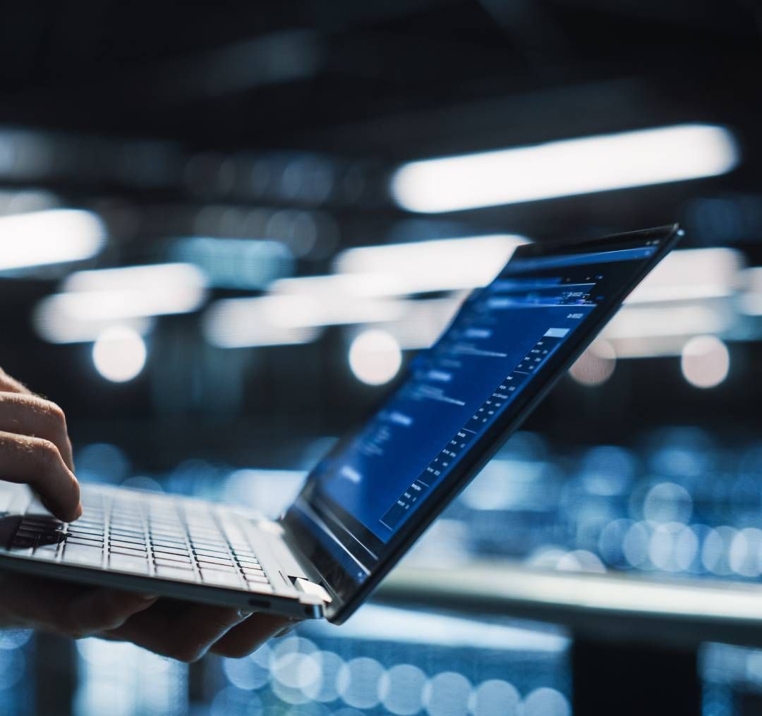 A person is typing on a laptop with a blue screen