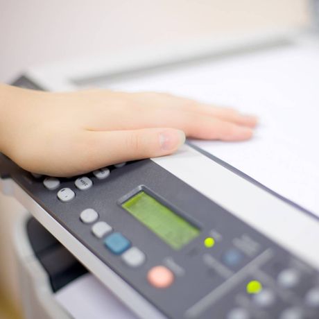 A person is pressing a button on a printer.
