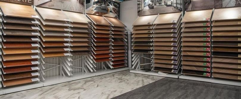 Samples of wood flooring in a showroom, arranged on tiered display racks.
